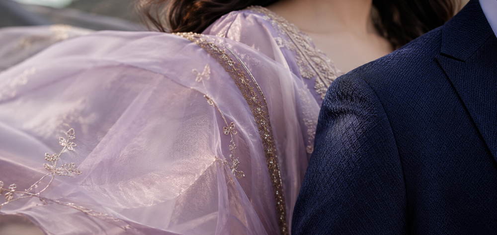 Close up detail of a flowing lavender organza dupatta and a tailored navy suit jacket