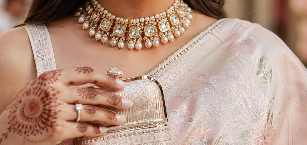 Close up of a guest's pearl choker necklace and pastel silk saree