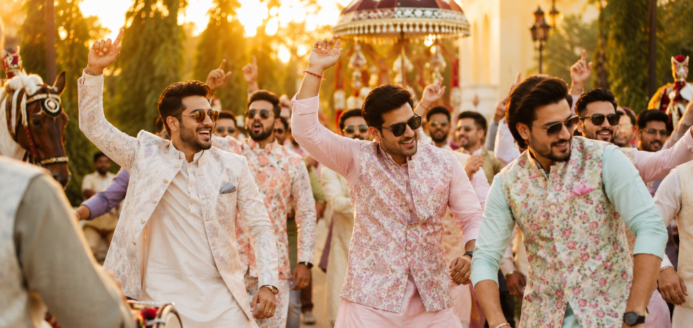 Stylish male guests dancing in the Baraat wearing sherwanis and Nehru jackets
