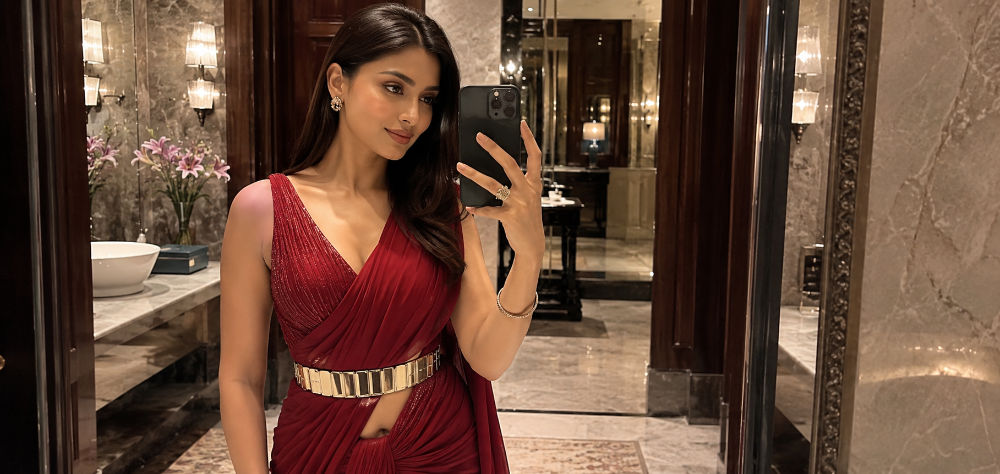 A stylish wedding guest taking a selfie in a mirror, wearing a contemporary ruby red pre-stitched draped outfit with a statement metallic waist belt, sleek straight hair and modern glowing makeup, luxurious hotel background 